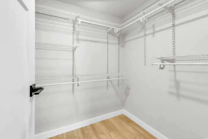 Walk-in closet featuring light wood-finish flooring, white walls, and a white adjustable wire shelving system