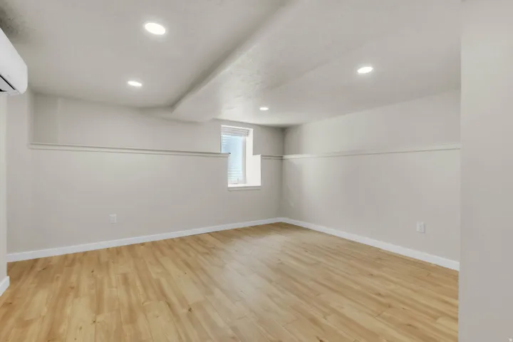 Spacious interior featuring light wood-finish flooring, recessed ceiling lights, and an installed split-system air conditioning unit