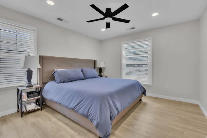 Room featuring neutral wall tones, wood-finish flooring, two windows with blinds, a ceiling fan, and recessed lighting
