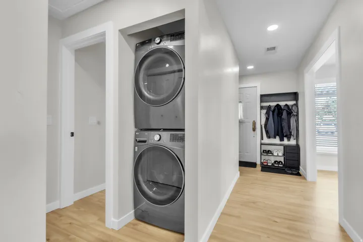 Integrated laundry area featuring a stacked washer and dryer, recessed lighting, and wood-finish flooring