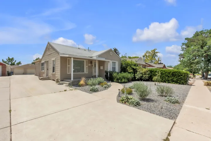 Ranch-style residence featuring neutral-toned siding, a covered front porch, and a gravel and shrubland front yard
