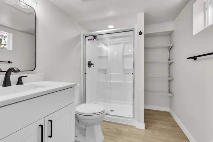Bathroom featuring a white vanity with integrated sink, quartz countertop, and black hardware