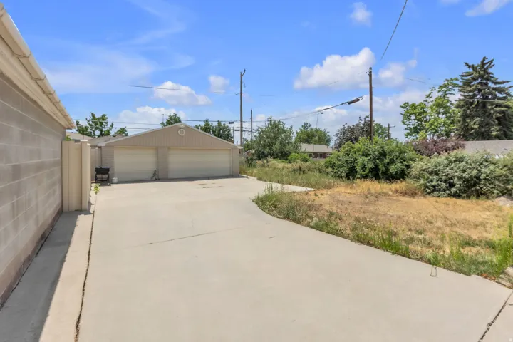 Concrete driveway leading to a detached two-car garage with white garage doors and siding