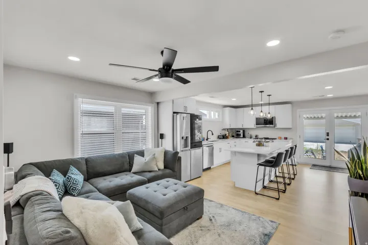 Open-concept living area with light wood-finish flooring, recessed lighting, a modern ceiling fan, and white walls