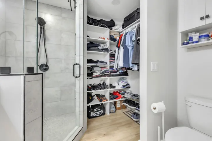 Glass-enclosed shower with matte black hardware, light-toned tile walls, and a white mosaic tile floor