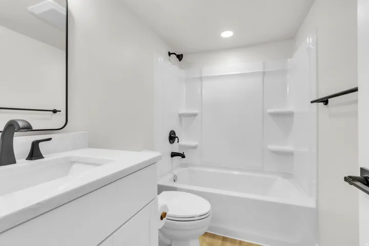Bathroom featuring a white vanity with an integrated sink, matte black faucet, and a rectangular framed mirror