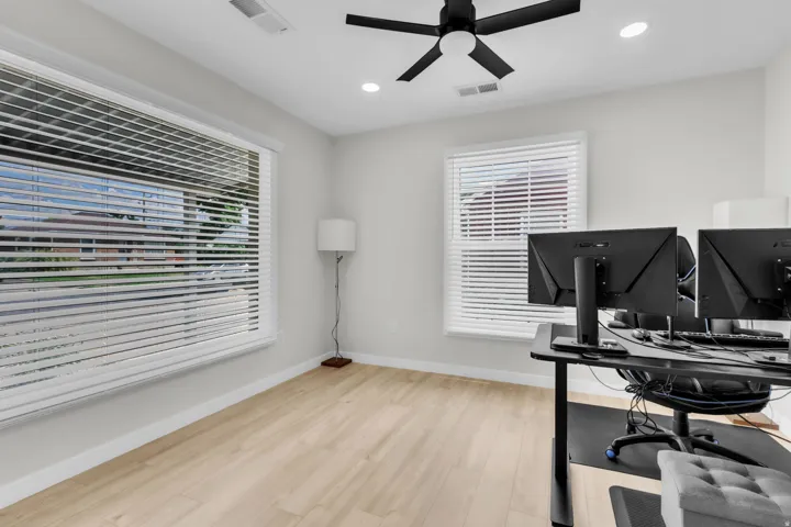 Bright room featuring wood-finish flooring, a large window with white blinds, and recessed lighting
