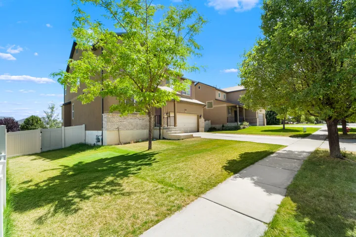 Contemporary residential exterior featuring a stucco facade with stone accents, a concrete driveway, an attached garage, and a manicured lawn