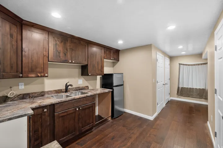 Full kitchen area featuring dark wood cabinetry, a double basin stainless steel sink, and stone countertops