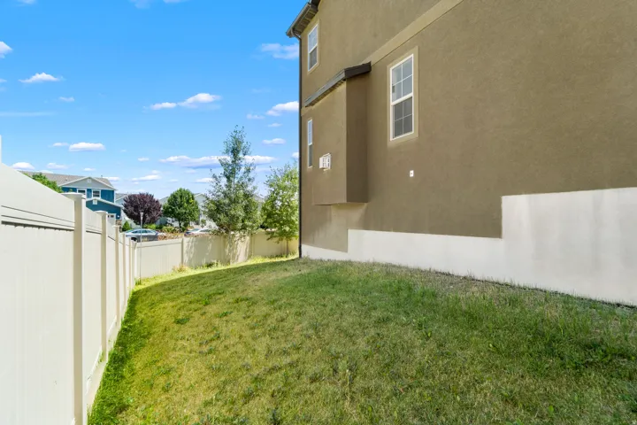 Fenced backyard featuring an established lawn, privacy fencing, and a stucco exterior