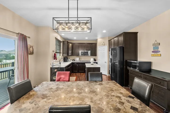 Open-concept kitchen and dining area featuring dark wood-finish cabinetry, stainless steel appliances, and a central island with countertop seating