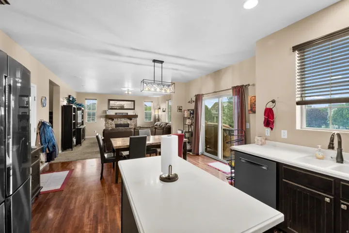 Kitchen island with white countertop and integrated sink, featuring dark cabinetry and stainless steel appliances