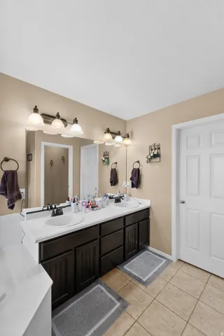 Dual vanity featuring white countertops, dark wood-finish cabinetry, and individual sinks