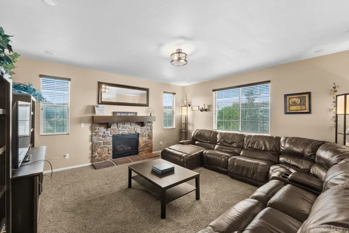 Living space featuring a stone-clad fireplace with a wood mantel, multiple windows, and recessed lighting