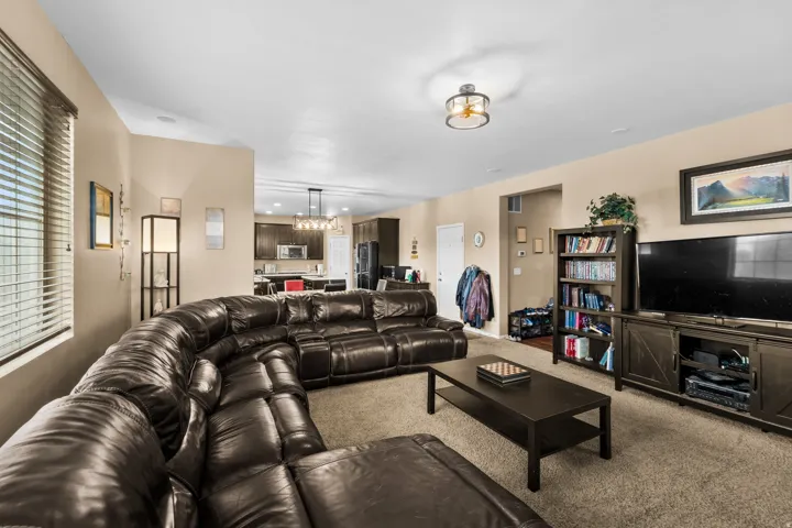 Spacious living area featuring neutral-toned walls, textured carpeting, and a modern semi-flush mount ceiling light fixture
