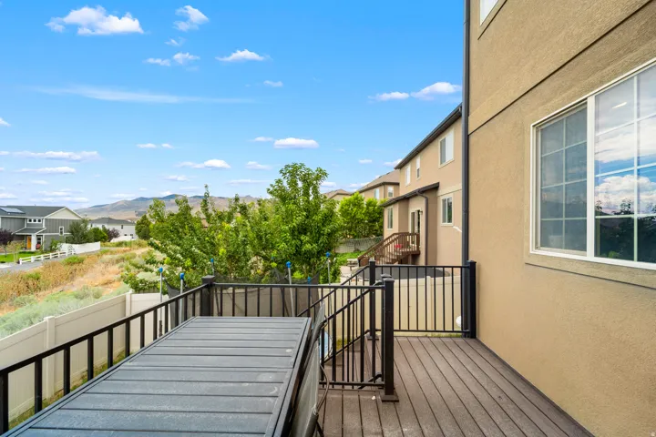 Spacious outdoor deck with composite decking, black metal railing, and a mountain backdrop