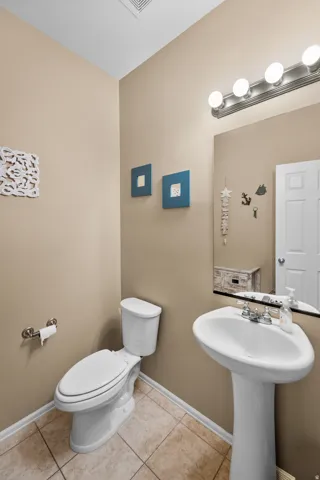 Powder room featuring a pedestal sink with chrome fixtures, a full-size mirror, and a classic white toilet