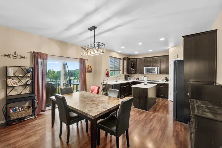 Open-concept kitchen and dining area featuring wood-finish flooring, dark cabinetry, and white countertops
