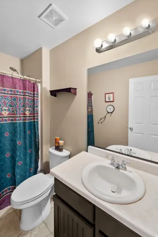 Bathroom featuring a vanity with a white oval sink, chrome faucet, and dark wood-finish cabinetry