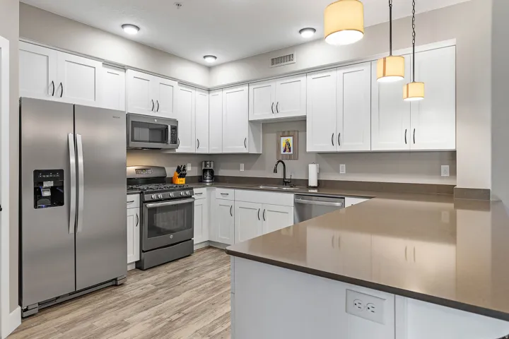 Modern kitchen featuring white shaker-style cabinetry, stainless steel appliances, and wood-finish flooring