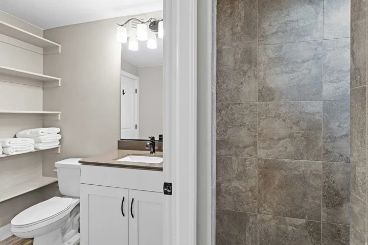 Bathroom featuring a single vanity with stone countertop, white cabinetry, and matte black hardware