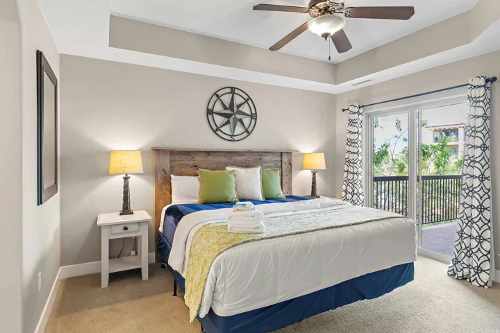 Spacious room featuring a tray ceiling, ceiling fan with light fixture, carpeted flooring, and direct access to an outdoor area through glass sliding doors