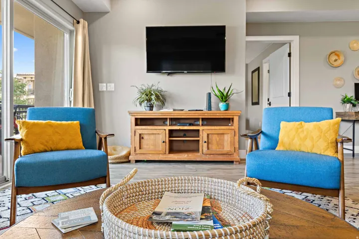 Spacious living area featuring light gray wall paint, wood-finish flooring, and a sliding glass door providing outdoor access