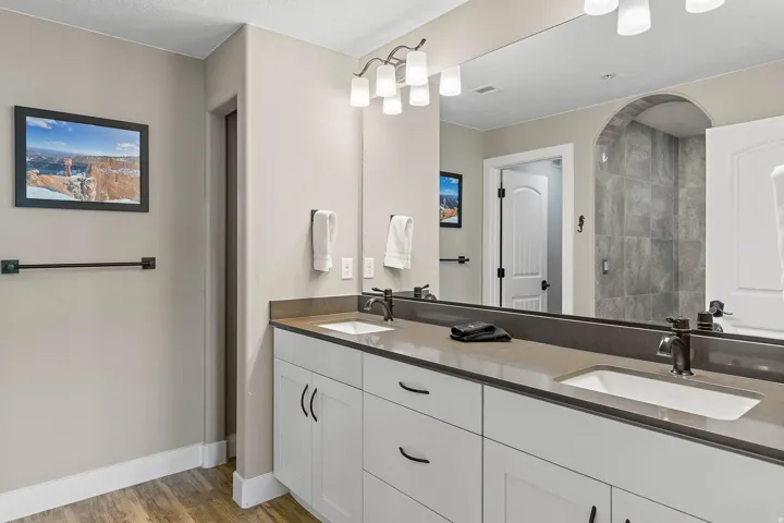 Dual vanity featuring white shaker cabinetry, dark countertops, and undermount sinks