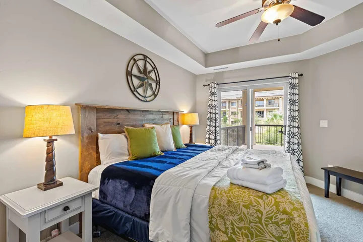 Room featuring a wood-finish headboard, tray ceiling, and a ceiling fan with integrated lighting