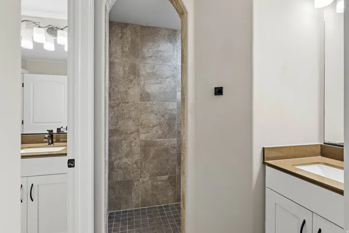 Walk-in shower with tiled walls and floor, featuring an arched entryway