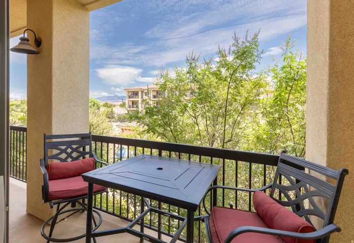 Outdoor balcony featuring a stucco column, black metal railing, and an exterior wall light fixture