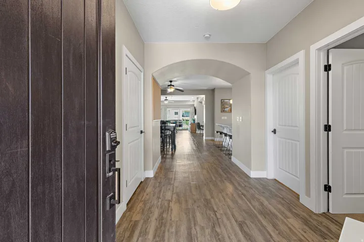 Entryway featuring wood-finish flooring, an arched doorway, white interior doors, and a dark-toned front door with contemporary hardware