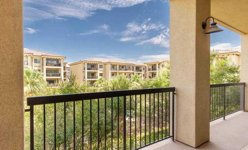 Exterior balcony featuring a black metal railing and a wall-mounted outdoor light fixture