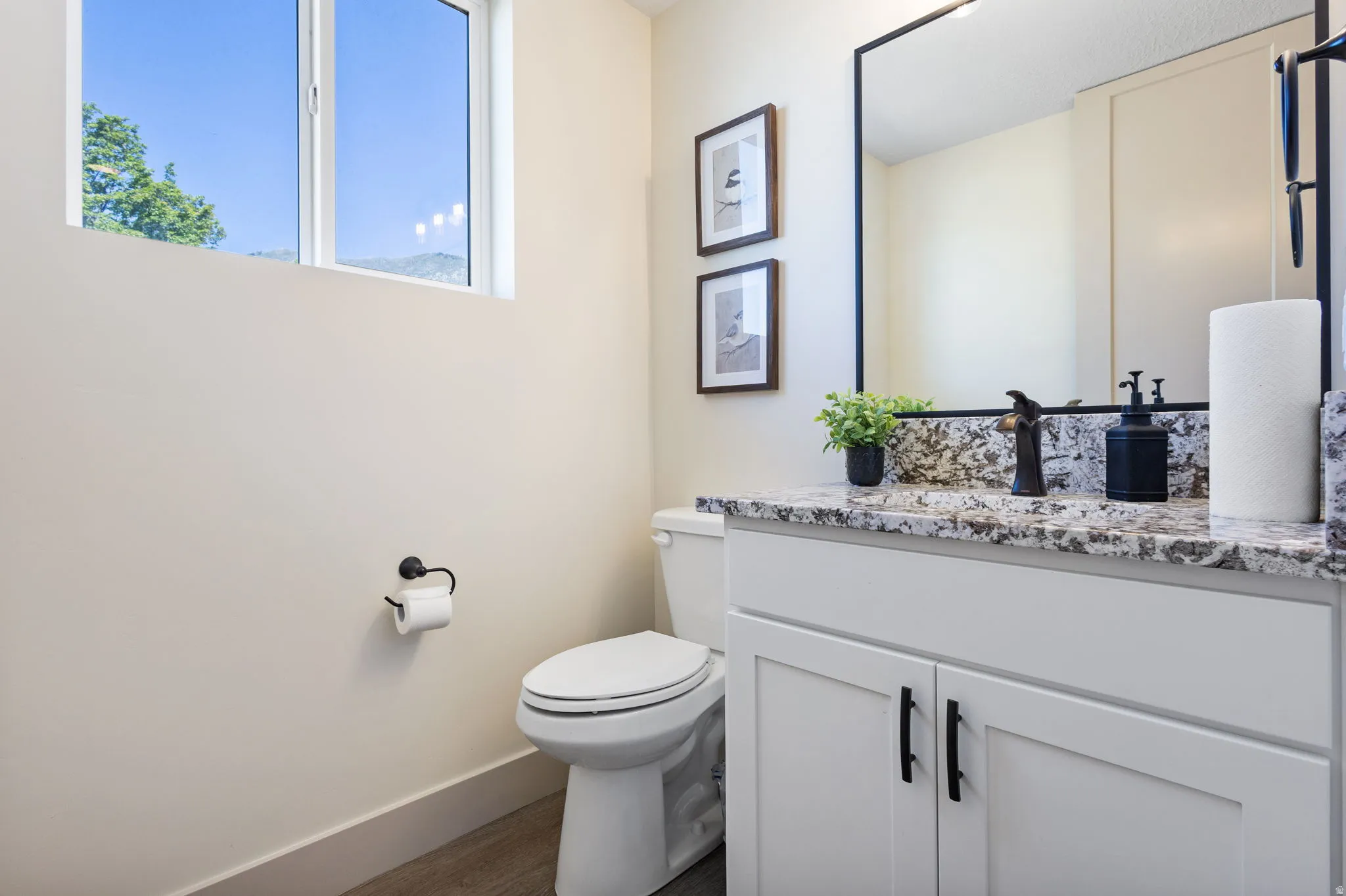 Bathroom vanity featuring a speckled countertop, dark bronze faucet, and a rectangular mirror with a black frame