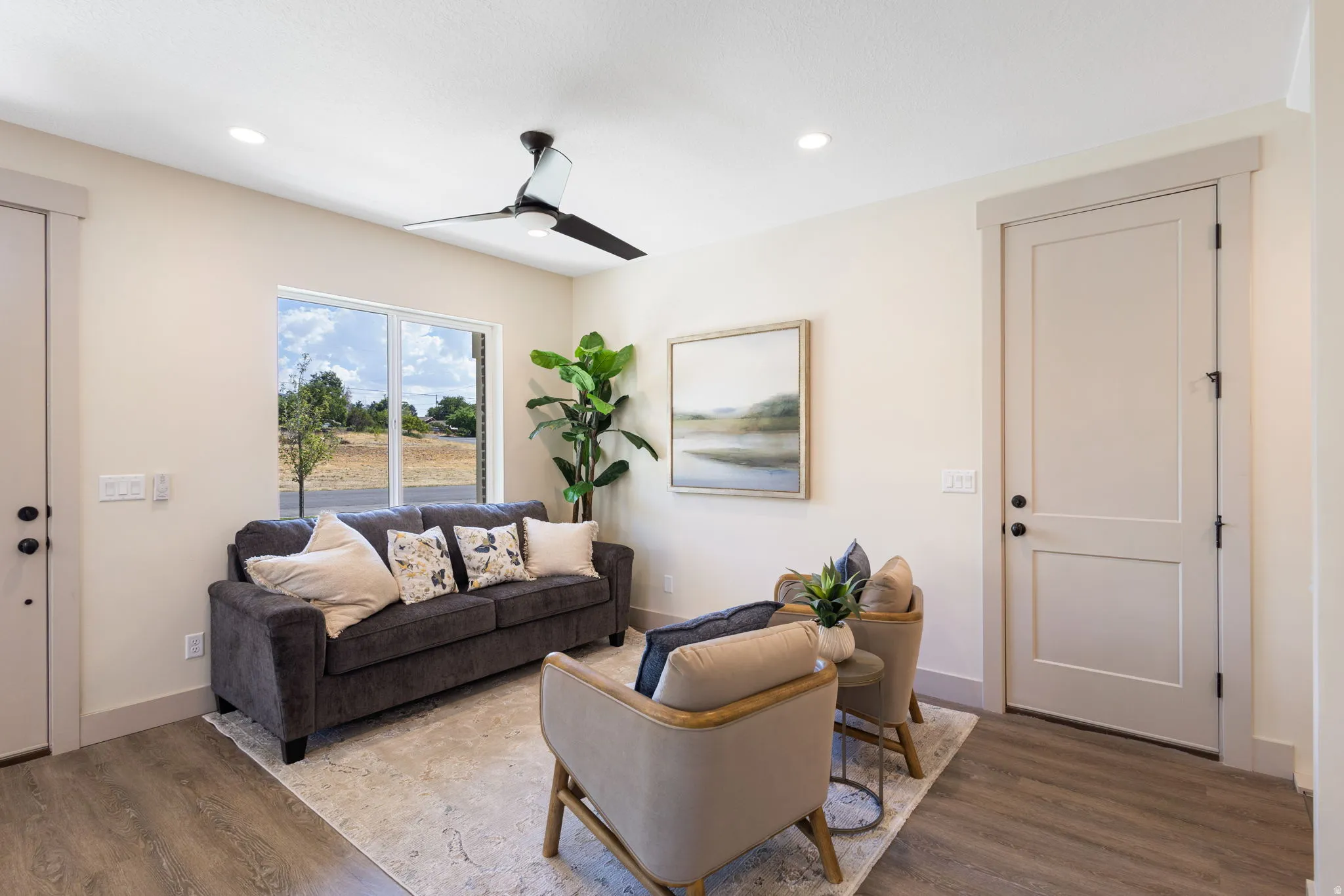 Recessed lighting illuminates this room featuring wood-finish flooring, a modern ceiling fan, and a large window