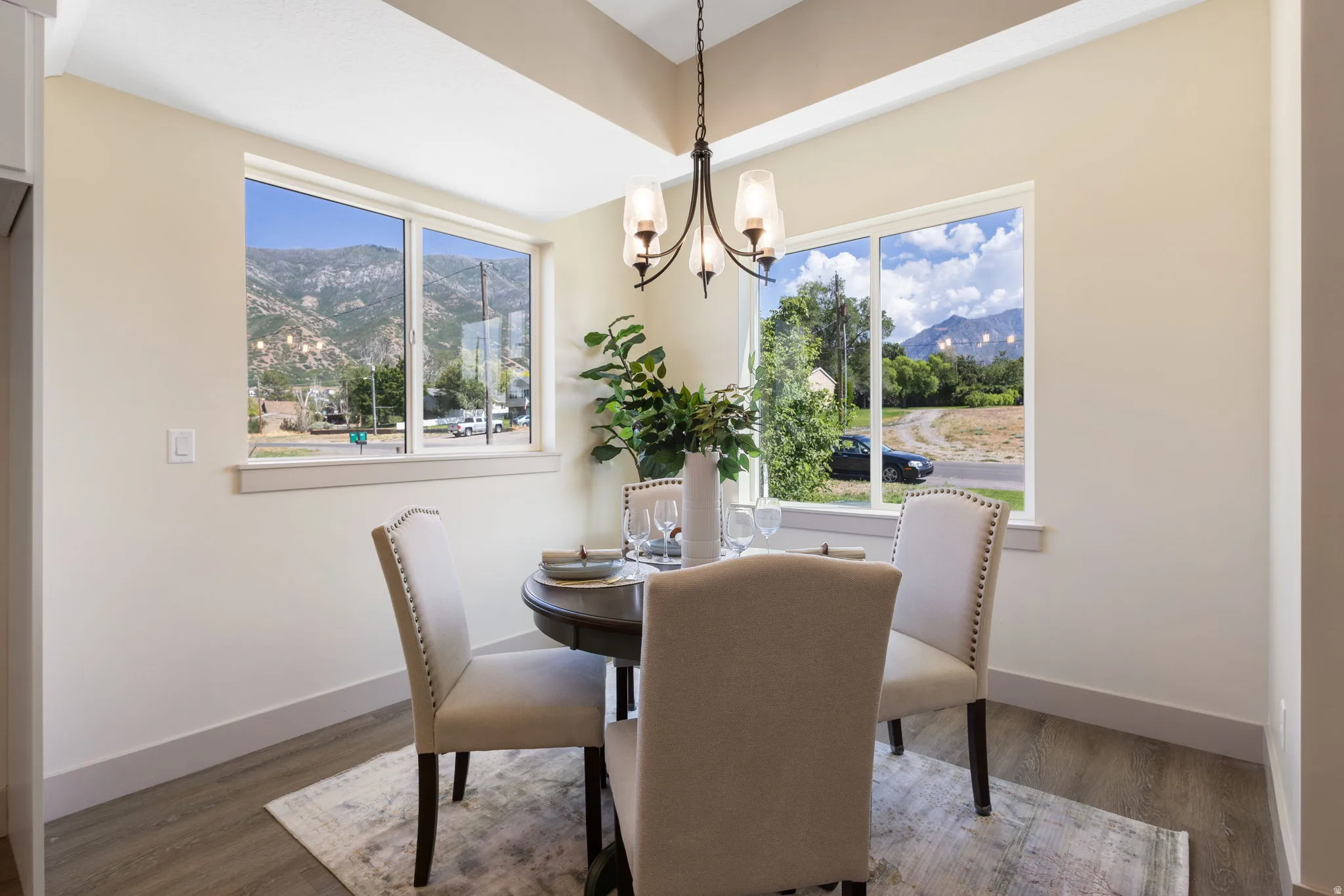 Dining area featuring a contemporary chandelier, two large windows, wood-finish flooring, and light-toned walls