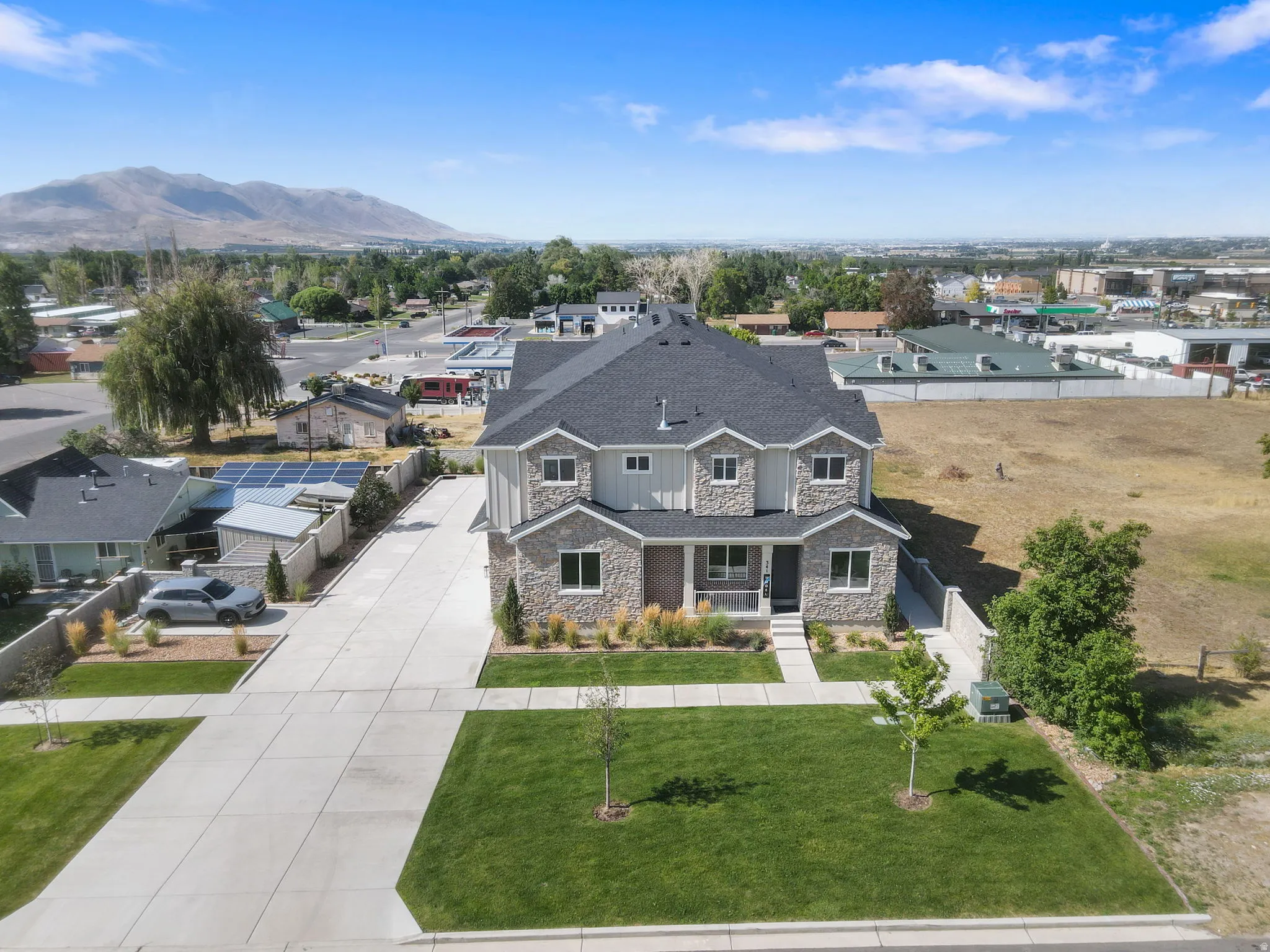 Contemporary two-story residence featuring a stone and siding exterior, dark shingle roof, and multiple window dormers