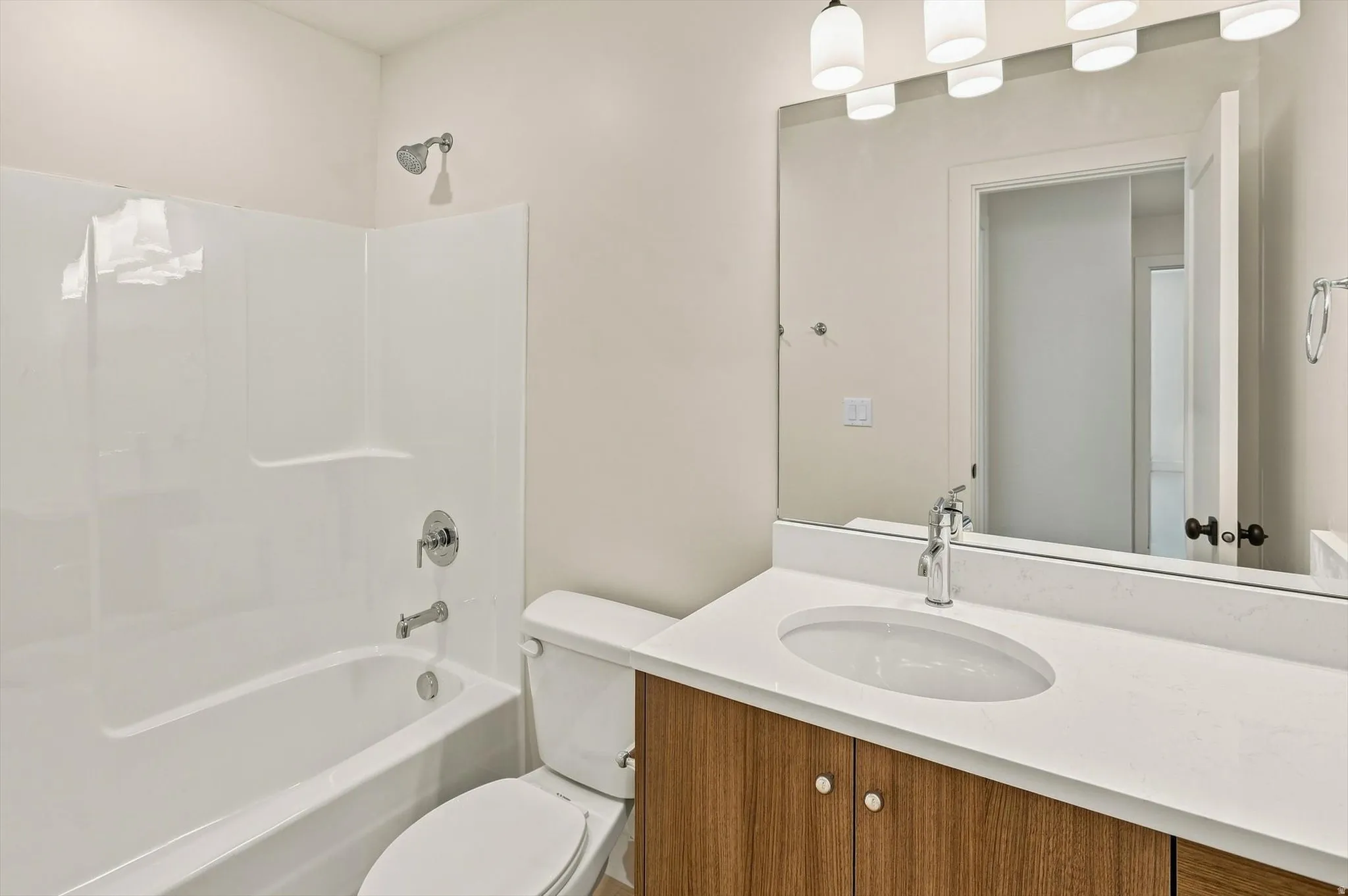 Bathroom featuring a full vanity with a white countertop and wood-finish cabinetry, an undermount oval sink, and a large wall mirror