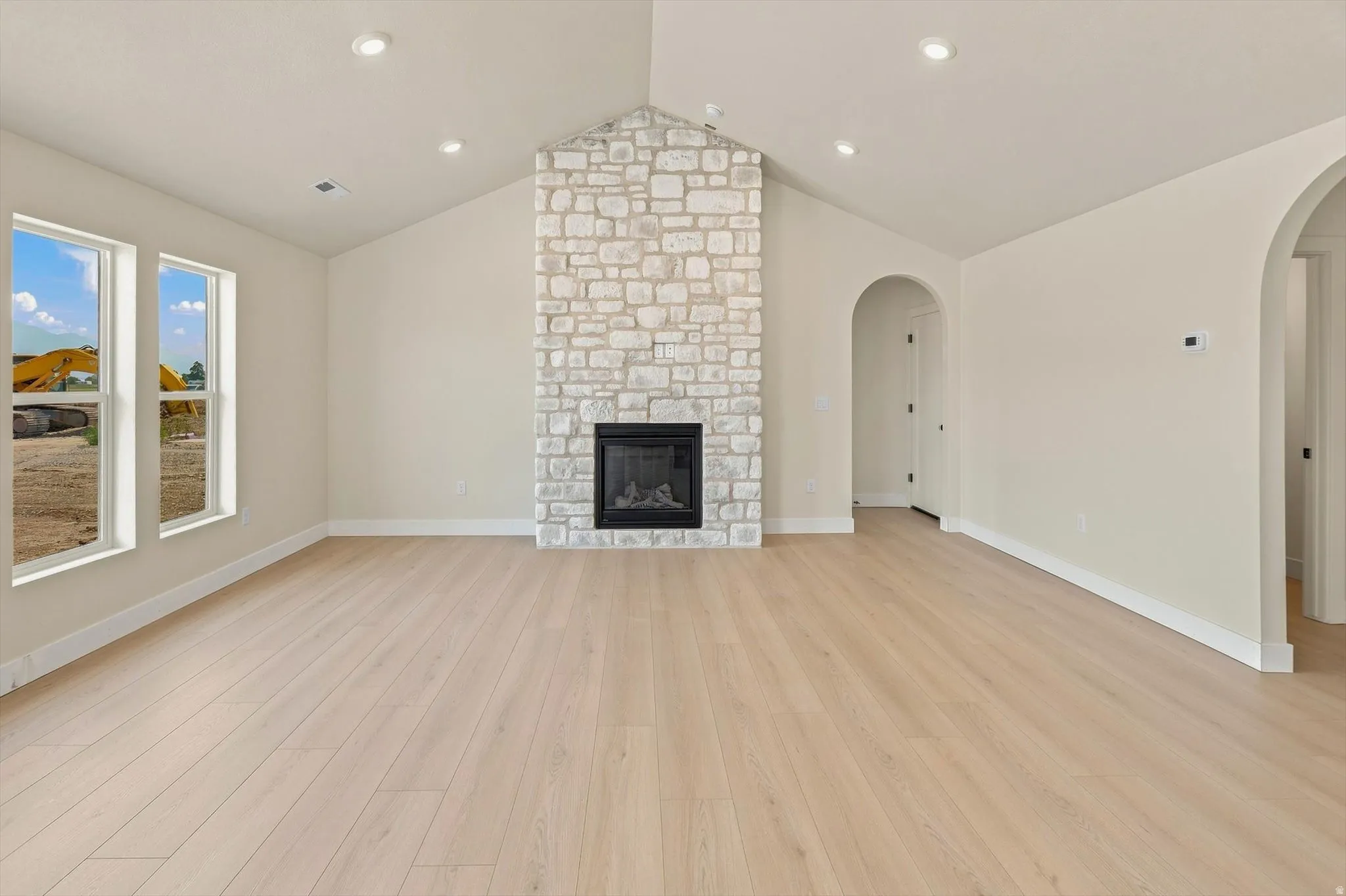 Spacious living area featuring a stone-clad fireplace and wood-finish flooring
