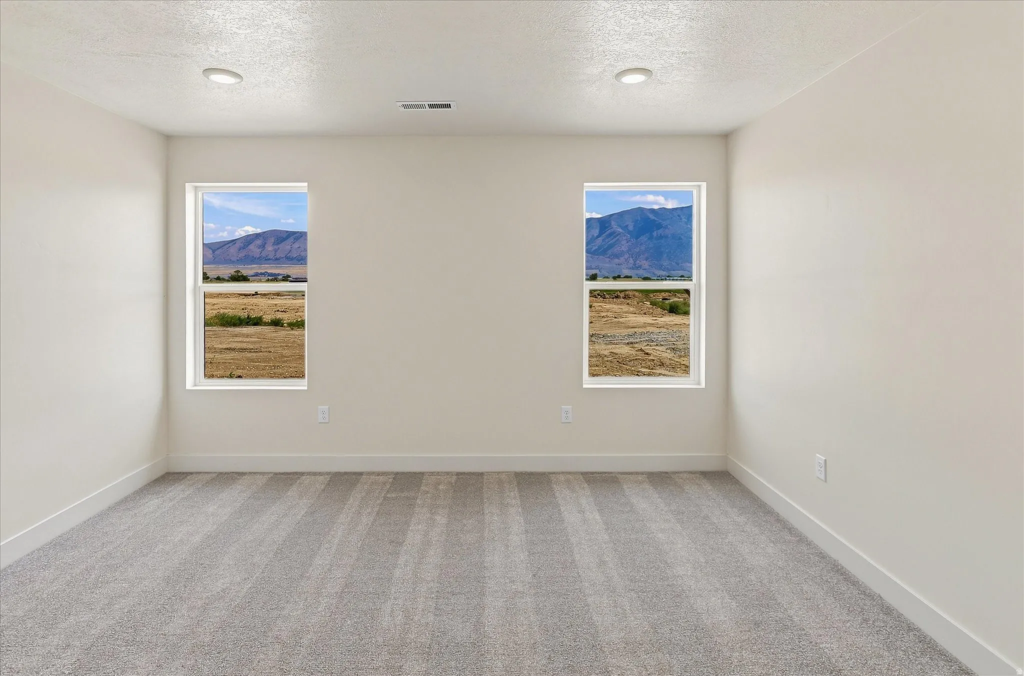 Bright interior space featuring two windows showcasing a distant mountain range and expansive open terrain