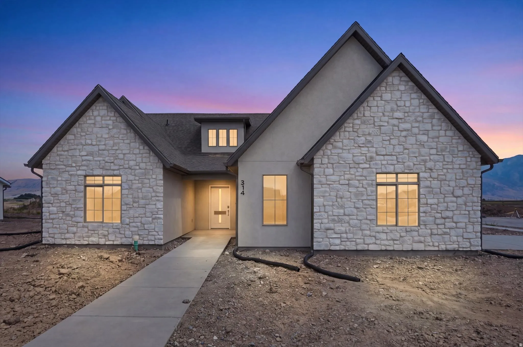 Modern stucco and stone exterior featuring multiple gables and a dormer with three rectangular windows