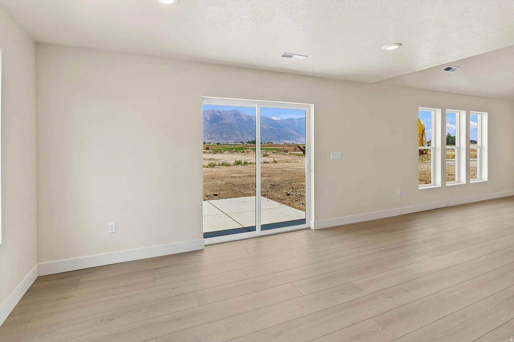 Open-concept living space featuring wood-finish flooring, recessed lighting, and a sliding glass door to an outdoor patio