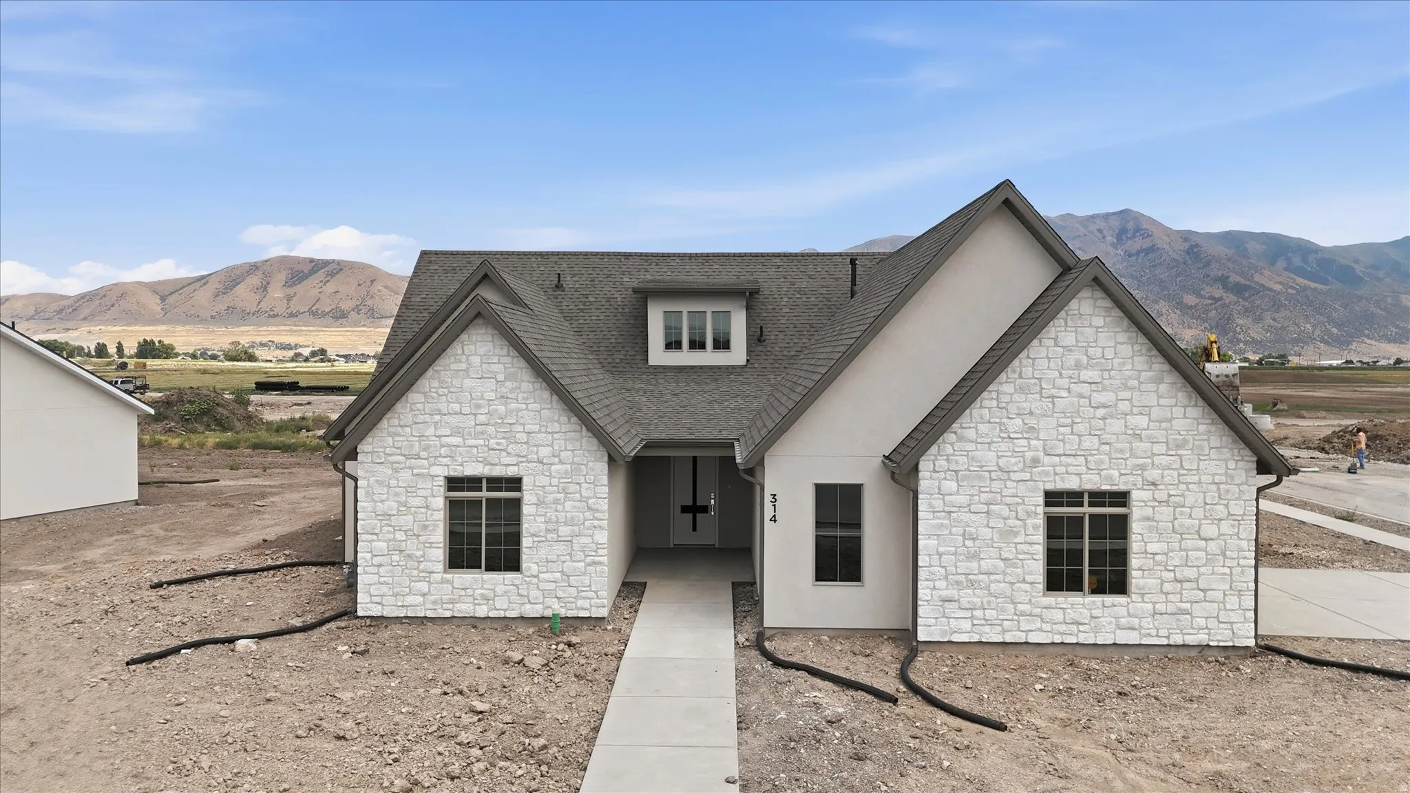 Contemporary-style residence featuring a gray asphalt shingle roof and light-toned stone veneer accents