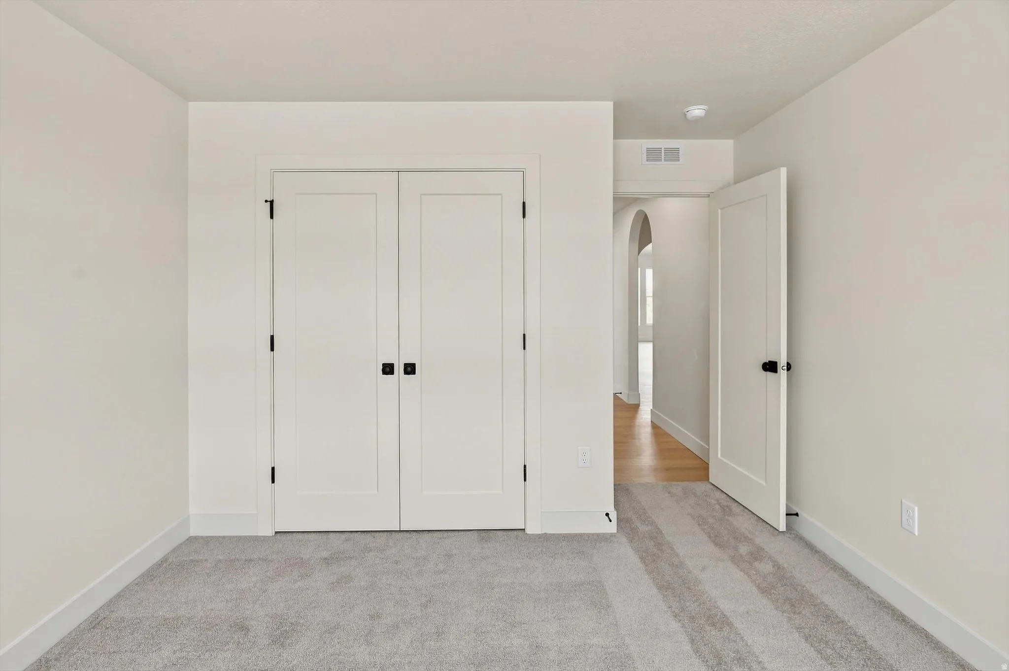 Neutral-toned room featuring light gray carpet, white baseboards, and white walls