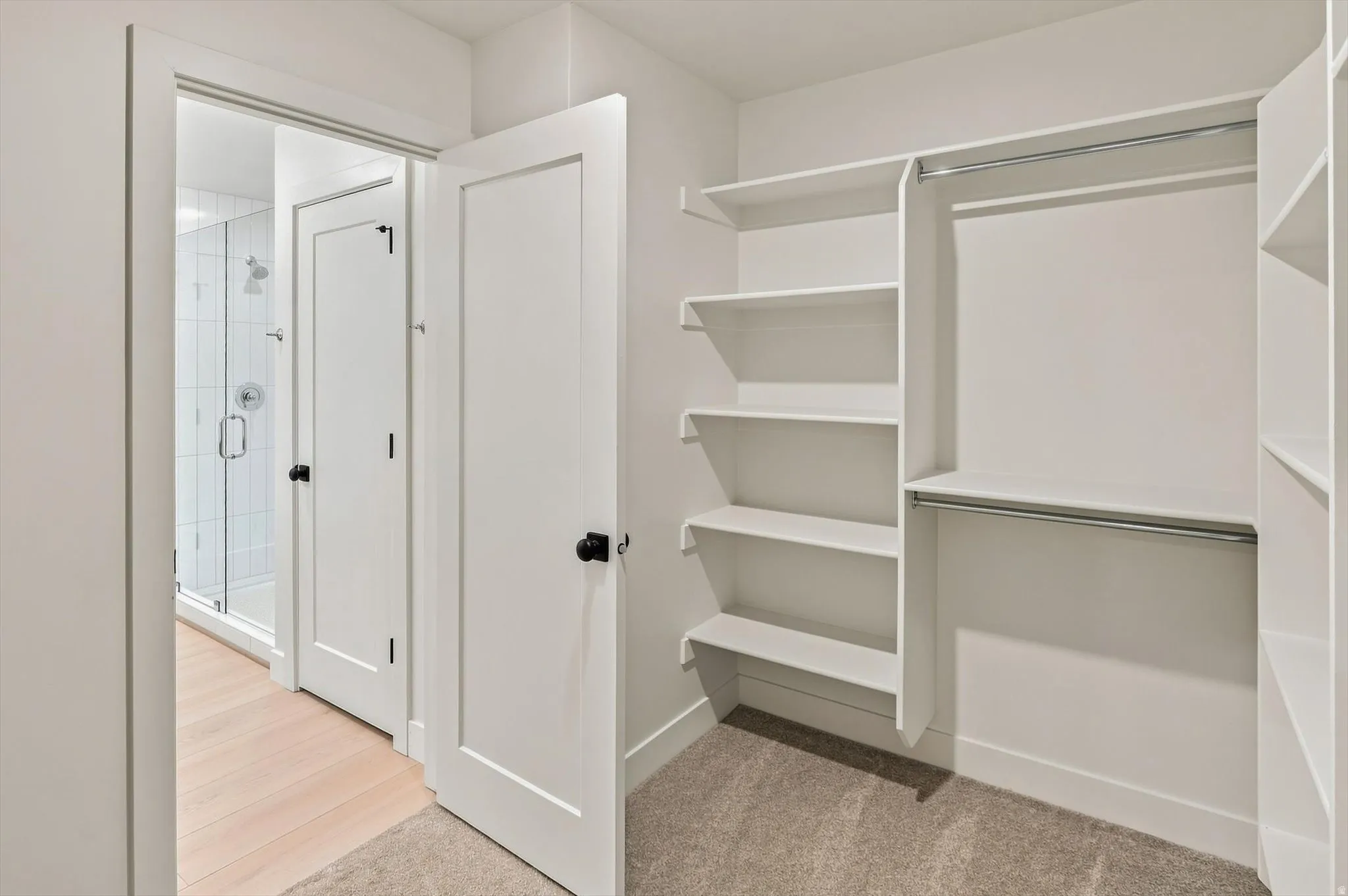 Walk-in closet with built-in shelving, dual hanging rods, and light-toned carpeting