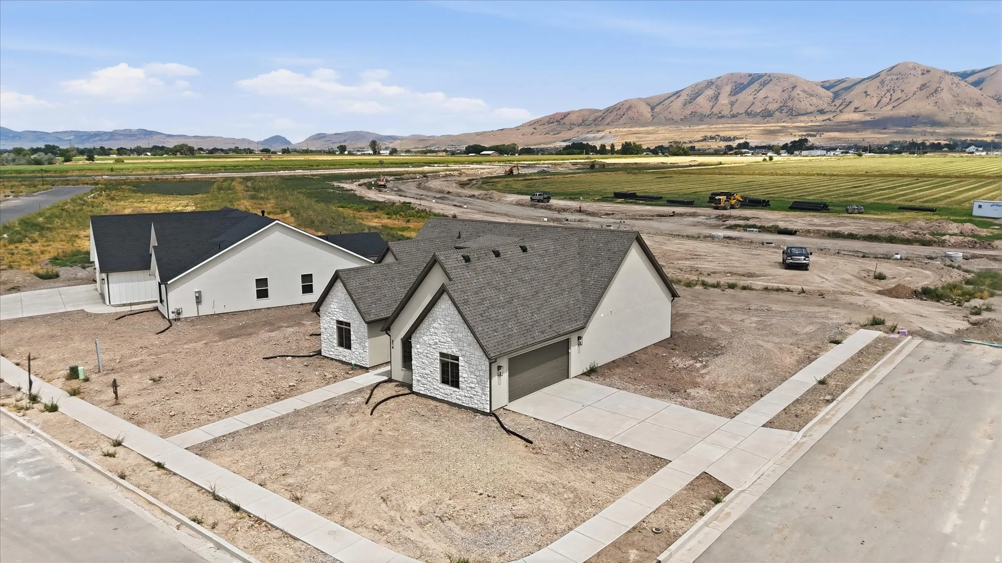 Newly constructed residence featuring a light-toned exterior with stone accents, dark-framed windows, and a dark shingled roof
