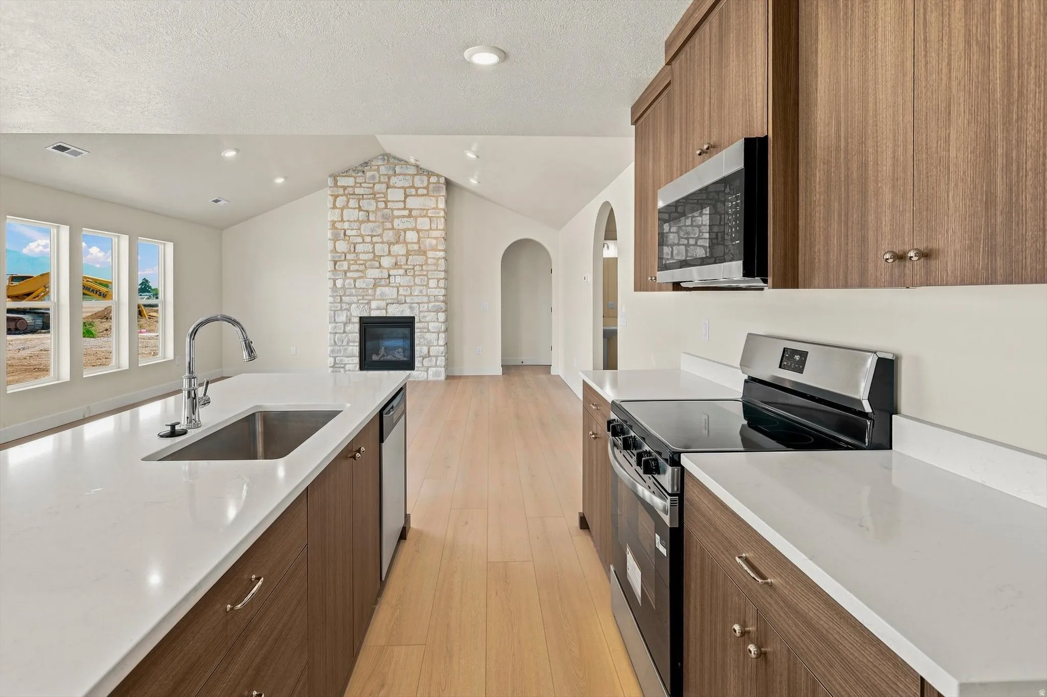 Kitchen featuring a large island with an undermount sink, light wood-finish cabinetry, stainless steel appliances, and white countertops