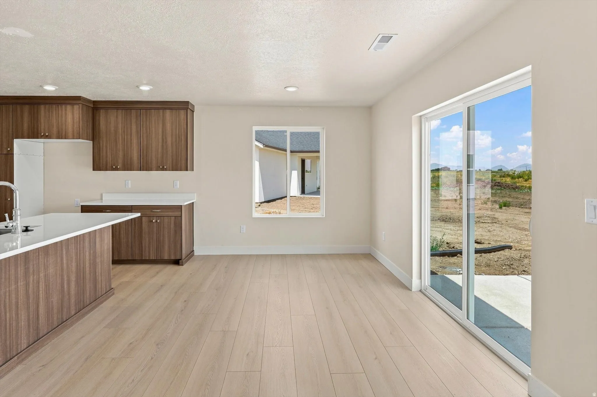 Open-concept living space with light wood-finish flooring, recessed lighting, and neutral wall paint