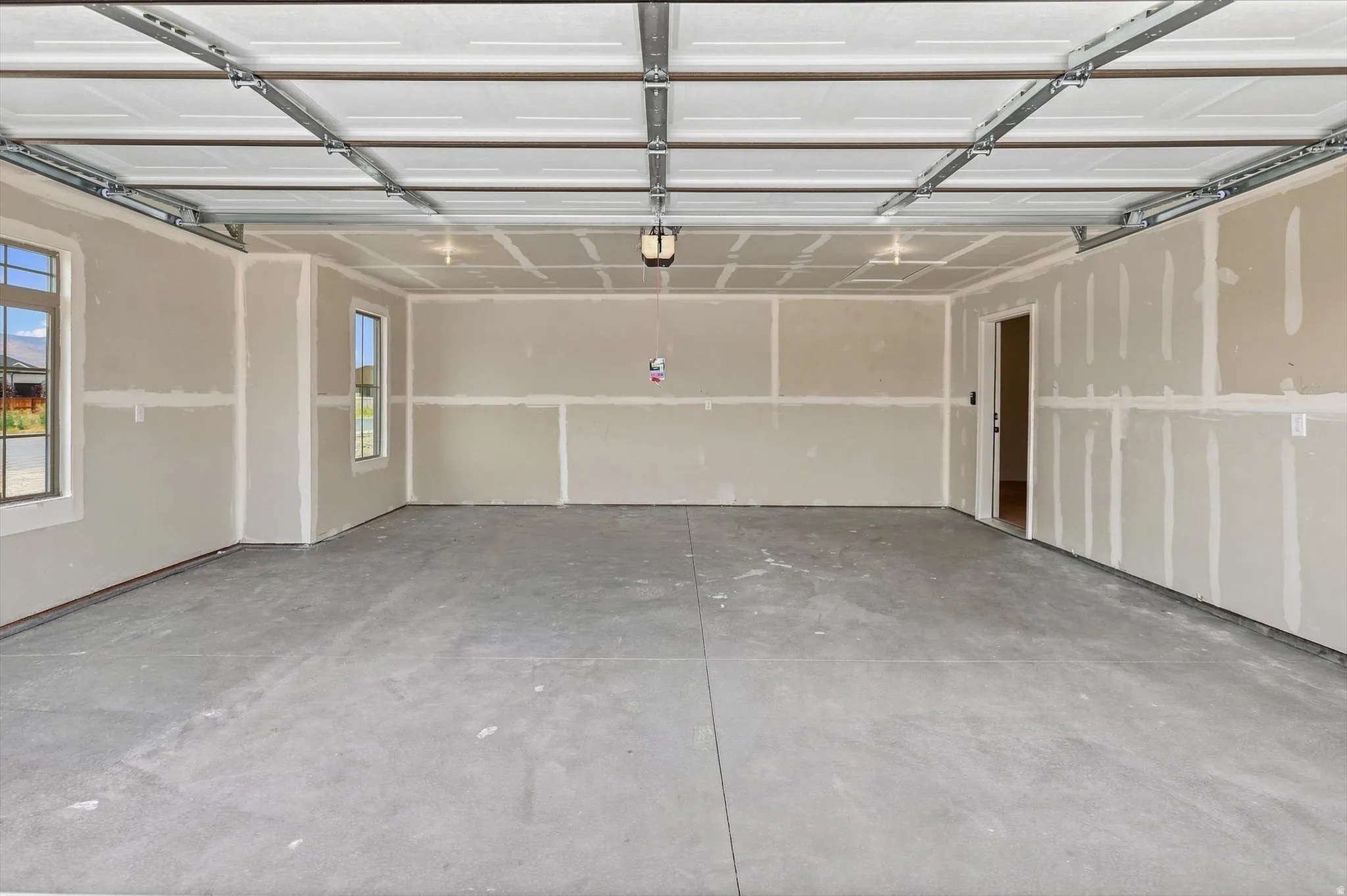 Spacious garage with a concrete floor, dual windows, and an interior access door