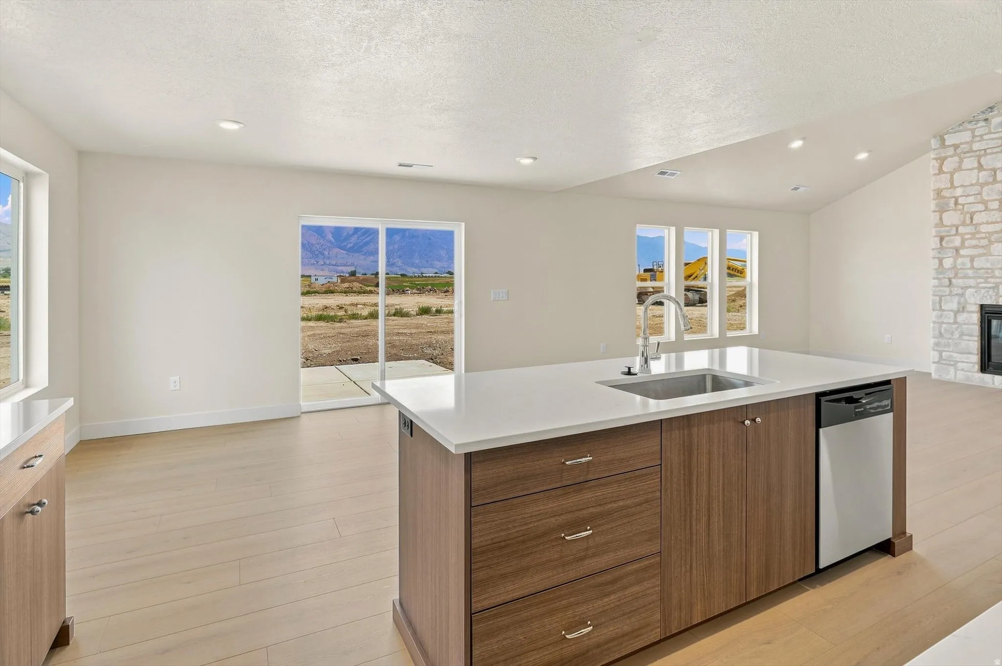 Kitchen island featuring a stainless steel sink with a high-arc faucet, integrated dishwasher, and wood-finish cabinetry